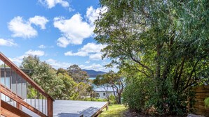 A wooden deck leading to a house with a view of a lake and mountains. - Marmoris Bay of Fires - A laid back coastal retreat with shimmering ocean views (Binalong Bay)