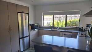Una cocina moderna con una isla integrada, electrodomésticos de acero inoxidable y un ventanal con vistas al verdor.