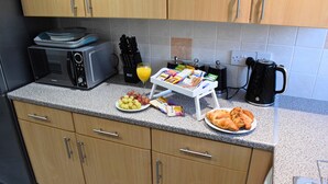 A kitchen with a microwave, toaster, coffee maker, and a small table with breakfast items. - Stylish 3-Bed House in Wolverhampton | Long Stays Welcome | Near Hospital (West Midlands)
