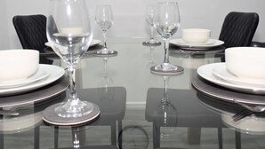 A dining table set with white plates, bowls, and wine glasses, surrounded by black chairs. - Stylish 3-Bed House in Wolverhampton | Long Stays Welcome | Near Hospital (West Midlands)