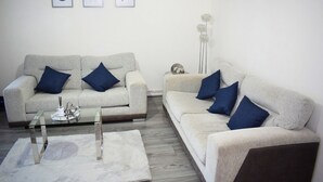 A living room with two sofas, a glass coffee table, and a floor lamp. - Stylish 3-Bed House in Wolverhampton | Long Stays Welcome | Near Hospital (West Midlands)