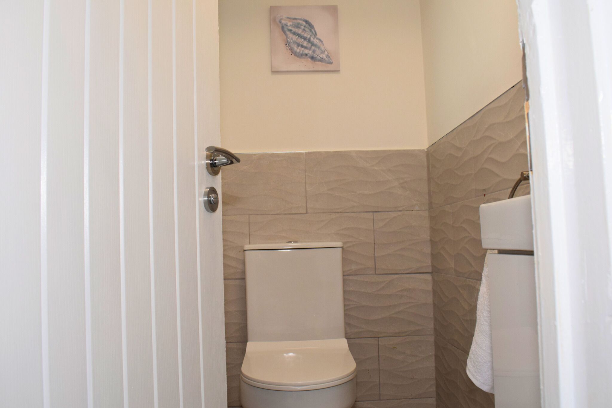 A bathroom with a toilet, a towel rack, and a textured wall.