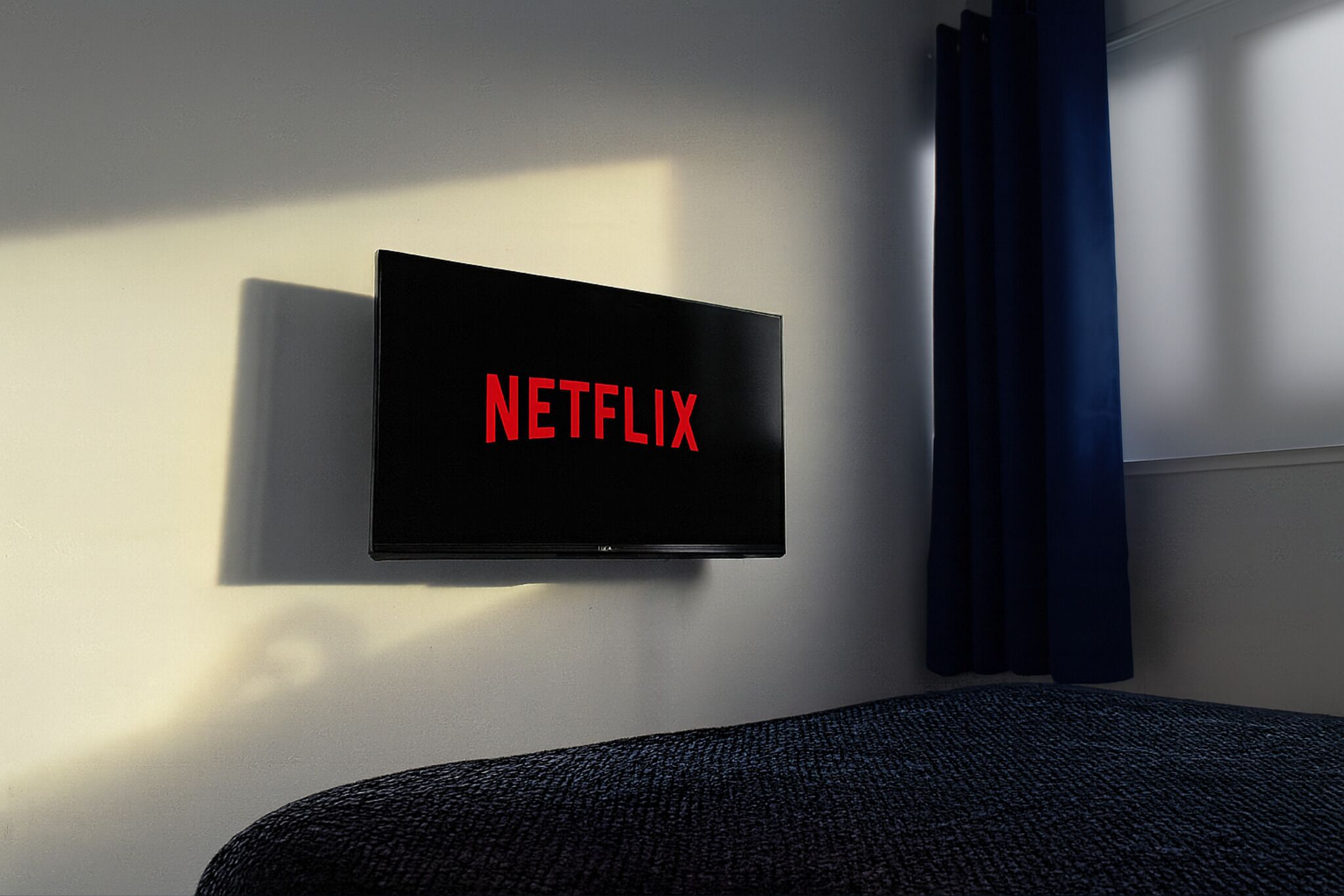 Un téléviseur fixé au mur, avec le logo de Netflix sur un mur blanc.