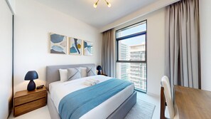 Ett modernt hotellrum med en stor säng, ett skrivbord och utsikt över stadsbilden genom fönstret.