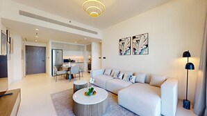 Una sala moderna con un sofá modular, una mesa de centro redonda y un comedor con sillas.