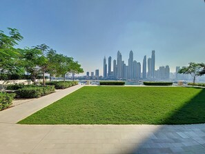 A grassy area with a pathway leading to a city skyline. - Stunning 1 Bed l Sea View l Private Beach Access (Emaar Beachfront)