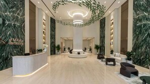 Un'ampia hall con una reception, zone relax e un grande lampadario.