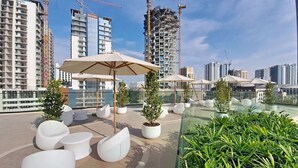 Una terrazza sul tetto con sedute bianche, piante in vaso e ombrelloni.