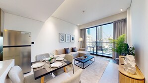 Ett modernt hotellrum med en matplats, en soffgrupp, ett soffbord och ett stort fönster med utsikt över staden.