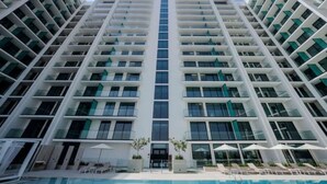 Un hôtel de grande hauteur doté d’un atrium central, de nombreux balcons et d’un espace piscine avec des chaises longues.