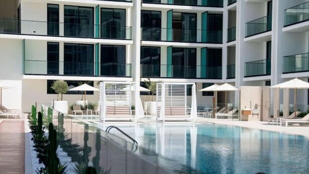 Un hôtel moderne doté d’une grande piscine intérieure, de nombreux balcons et de chaises longues.