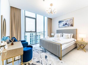 Ein modernes Hotelzimmer mit einem großen Bett, einem Schreibtisch, einem Stuhl und Blick auf die Stadt durch große Fenster.