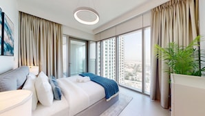Una habitación de hotel moderna con una cama grande, una mesita de noche, una planta en maceta y un amplio ventanal con vistas a la ciudad.