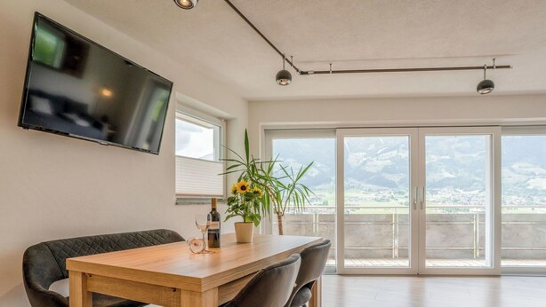 Un comedor moderno con una mesa y sillas de madera, una planta en maceta y una botella de vino.