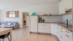 Una cocina moderna con armarios blancos, encimera de madera y horno empotrado.