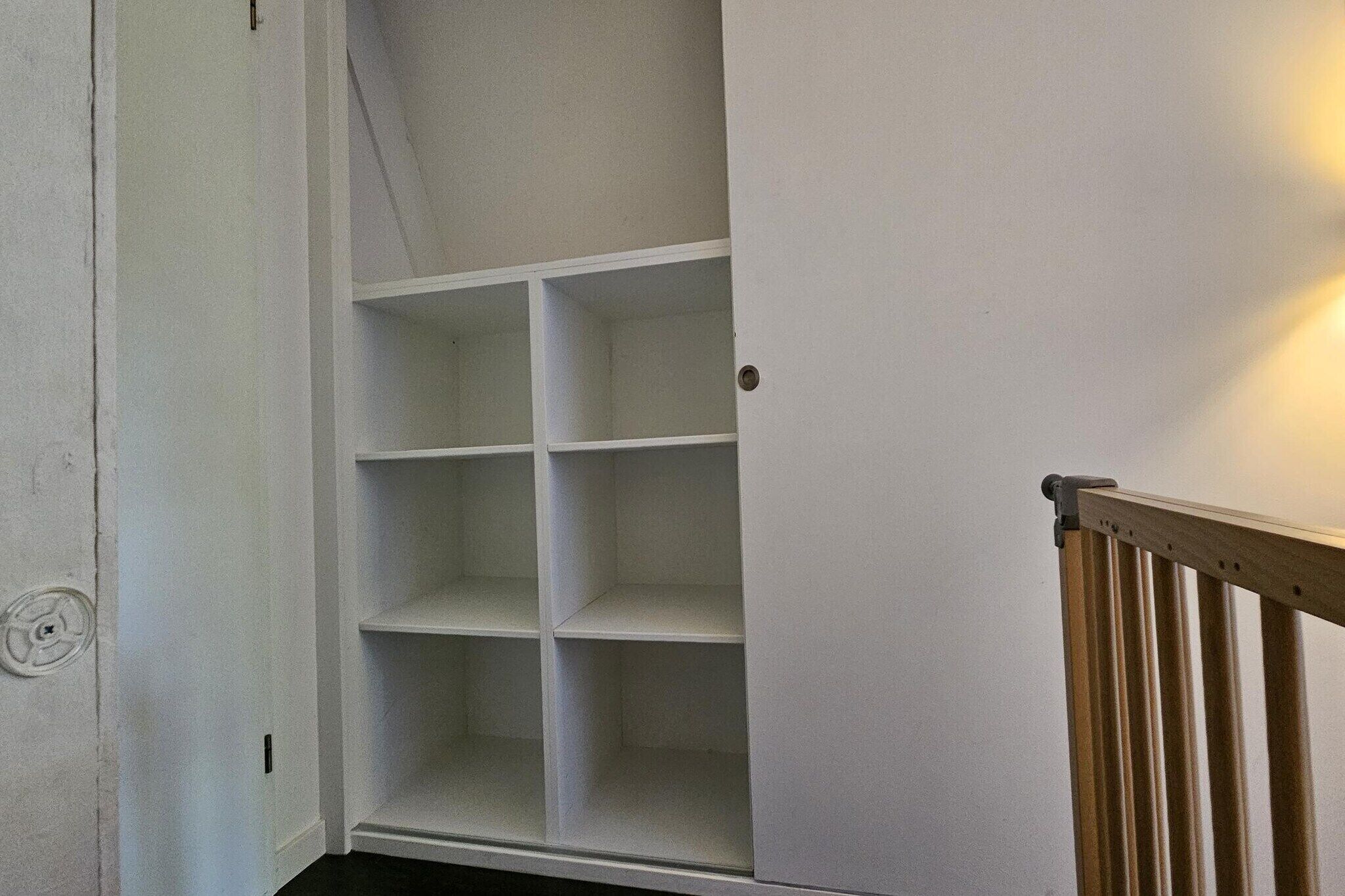 A white closet with multiple shelves and a wooden door.