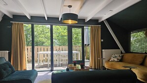 Una sala de estar moderna con un sofá, una mesa de centro y un amplio ventanal corredera que da a un patio exterior.