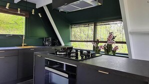 Una cocina moderna con estufa a gas, horno empotrado y ventana con vista a la vegetación.