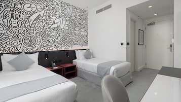 Ein modernes Hotelzimmer mit zwei Betten, einem Schreibtisch und einem großen, abstrakten Wandbild.