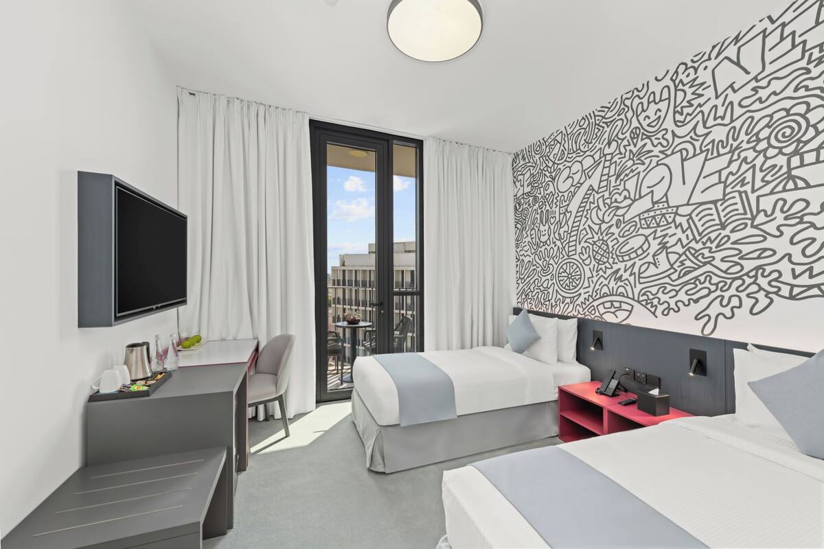 Una habitación de hotel moderna con una cama grande, un escritorio y un televisor.