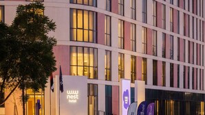 A modern hotel with a curved facade, multiple windows, and a well-lit entrance. - Nest Hotel, Aljada (Sharjah)