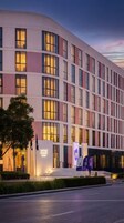 Un hotel moderno con fachada curva, múltiples ventanas y una entrada bien iluminada.