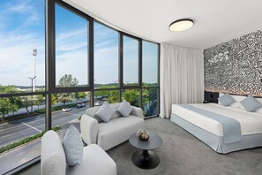 Moderni hotellihuone, jossa on suuret ikkunat, sohva, sänky ja pieni pöytä.
