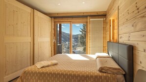 Un dormitorio con cama, ventana y vistas a montañas, además de paredes de madera.