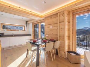 A modern kitchen with wooden walls and a dining area with a view of mountains. - Nice apartment for 6 people with WIFI, TV, terrace and pets allowed (Zerbi)