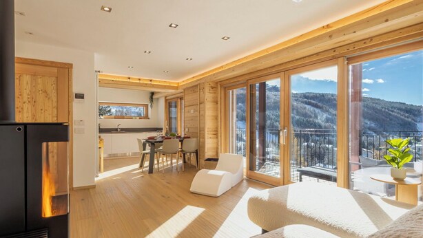 Un interior moderno con cocina, comedor y balcón con vistas a la montaña.
