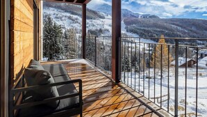 Un balcón de madera con vistas a montañas nevadas y cielo despejado.