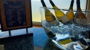 A bar area with a menu board and a glass of ice with wine bottles. - Albergo Trattoria Al Taj (Sevegliano)