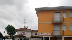 A parking lot with several cars and a building with a sign that reads "Alberto Alti". - Albergo Trattoria Al Taj (Sevegliano)