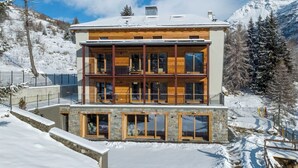 Un immeuble en bois à plusieurs étages, doté de balcons, de grandes fenêtres et d’une fondation en pierre.