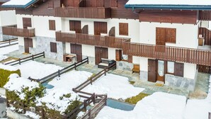 A multi-story chalet with wooden balconies, stone walls, and a snow-covered roof. - Lovely apartment for 4 people with WIFI, TV and pets allowed (Isolaccia)