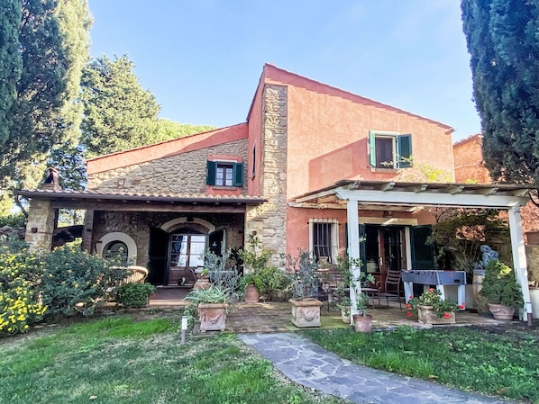 Une maison en pierre avec un patio couvert et un jardin.