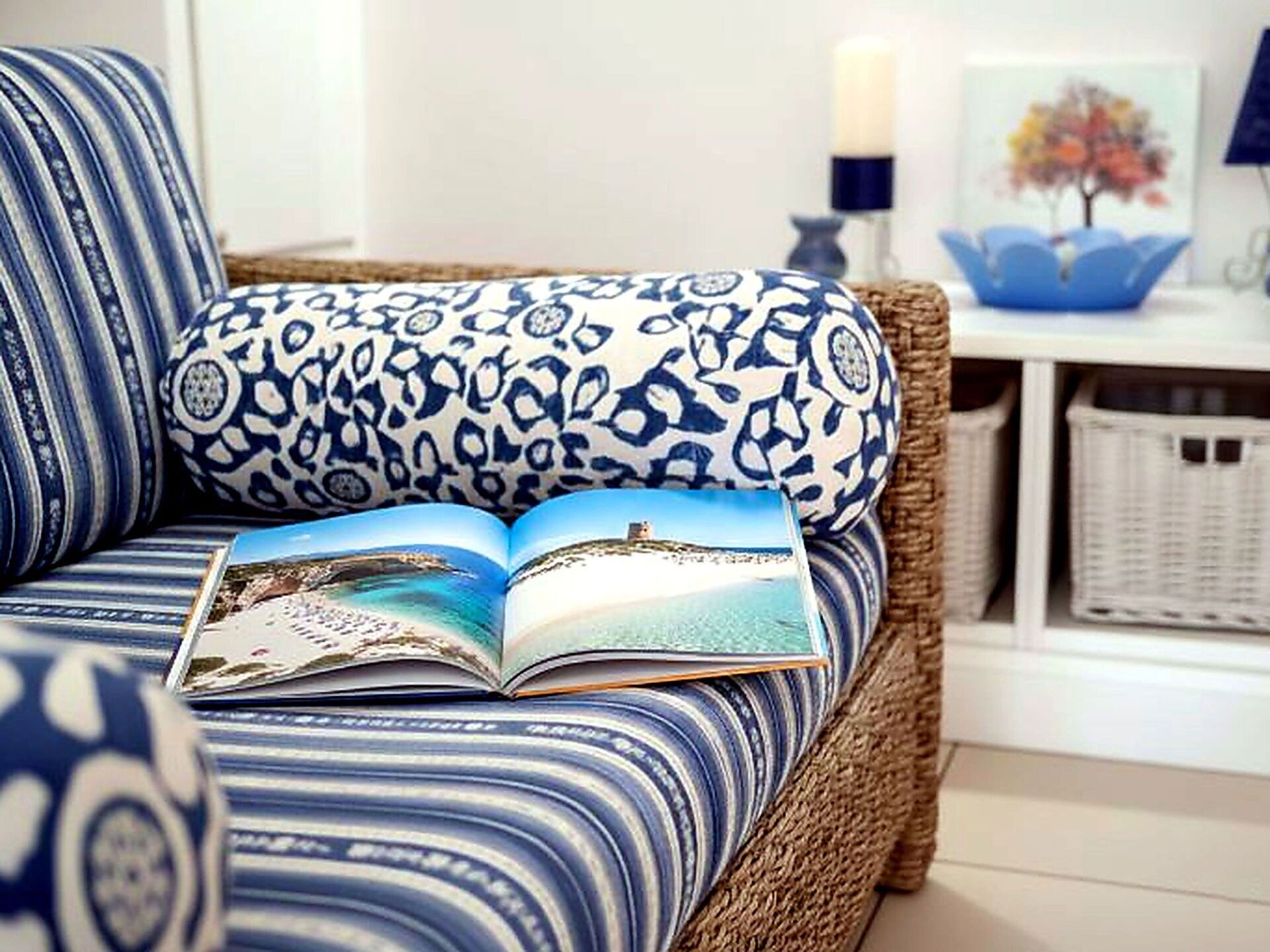 Ein blau-weiß gemustertes Sofa mit einem Buch, einer Kerze und einem gerahmten Bild auf einem Regal.