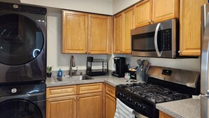 A modern kitchen with wooden cabinets, stainless steel appliances including a microwave, stove, and dishwasher, and granite countertops.
