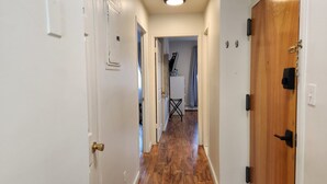 A hallway with wooden flooring, white walls, and a wooden door on the right.