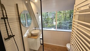 A modern bathroom with a large window, a round mirror, and a wooden vanity. - Comfortable Chalet near Durbuy Center (Durbuy)