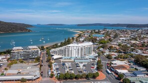 A coastal town with a prominent circular building, a marina with boats, and a parking lot. - Ocean Jewel, TOP NOTCH (ETTALONG BEQCH)