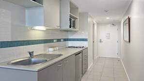 A modern kitchen with white cabinets, a stainless steel sink, and a blue-tiled backsplash. - Ocean Jewel, TOP NOTCH (ETTALONG BEQCH)