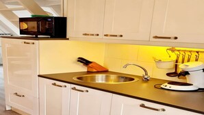 A modern kitchen with white cabinetry, a stainless steel sink, a microwave, a coffee maker, and a knife block. - Renovated Ardennes Chalet with Patio (Durbuy)