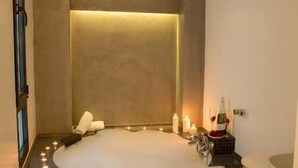 Un baño moderno con una bañera independiente, un tocador con espejo y una pequeña mesa con artículos de aseo.