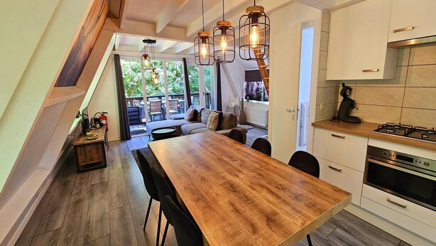 A modern kitchen with a wooden dining table, white cabinets, and a built-in oven. - Comfortable Fenced Chalet in Durbuy (Durbuy)