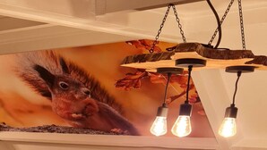 Un plafond orné d’une étagère en bois portant trois ampoules et d  ’une fresque représentant un écureuil.