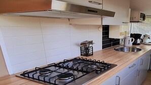 Une cuisine moderne équipée d’une cuisinière à gaz, d’un évier en acier inoxydable et d’un plan de travail en bois.