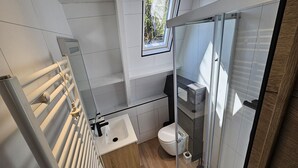 Ein modernes Badezimmer mit Duschkabine aus Glas, einem weißen Waschbecken und einer Toilette.