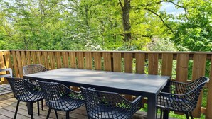 Eine Holzterrasse mit einem Tisch und vier Stühlen.