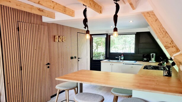 Eine moderne Küche mit einer Holztheke, Barhocker und Blick ins Freie.